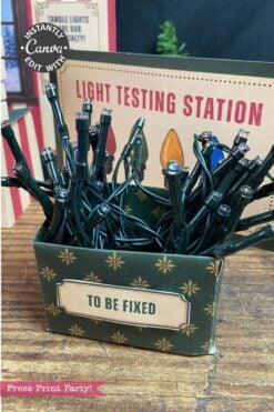 A box labeled “TO BE FIXED” holds tangled string lights in front of a sign that reads “LIGHT TESTING STATION,” with 6 Pink Coquette Halloween Ghost Round Labels peeking out among other holiday decor elements visible in the background.