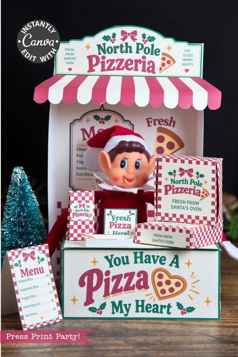 A festive elf doll sits in a North Pole Pizzeria booth, surrounded by mini pizza boxes decorated with 6 Pink Coquette Halloween Ghost Round Labels, a menu card, and a sparkly tree—all under a red-and-white striped awning with holiday-themed décor.