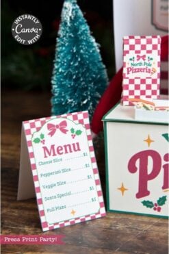 A festive menu card and pizza box showcase a charming “North Pole Pizzeria” theme with holiday decor in the background, including a small Christmas tree. Accented by 6 Pink Coquette Halloween Ghost Round Labels, the menu features cheese, pepperoni, veggie, and Santa pizza slices for $1 each.
