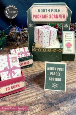 A festive North Pole package scanner setup made from paper, with labeled boxes for “to scan” and “cleared” parcels featuring the 6 Pink Coquette Halloween Ghost Round Labels, festive decor, and a sign reading “North Pole Parcel Sorting.”.