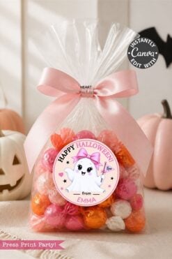 A clear bag of orange, pink, and white candies with a pink bow is topped with a ghost-themed label from the 6 Pink Coquette Halloween Ghost Round Labels set that reads “Happy Halloween from Emma.” White pumpkins decorate the background.