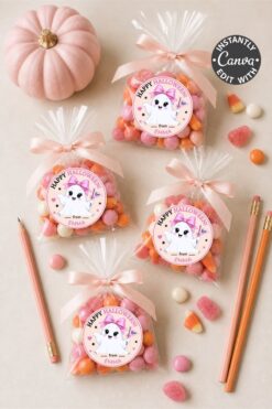 Six bags of Halloween candies with adorable Pink Coquette Halloween Ghost Round Labels featuring cute unicorns, a small pink pumpkin, pink pencils, and scattered heart-shaped candies on a light surface.