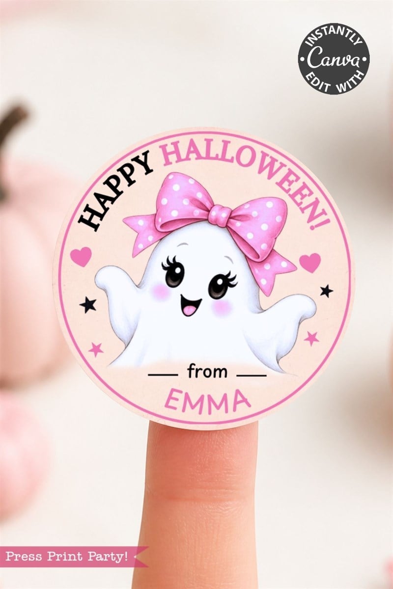 A round pink sticker from the 6 Pink Coquette Halloween Ghost Round Labels collection showcases a cute smiling ghost wearing a pink polka-dot bow with the text “Happy Halloween! from EMMA.” The sticker is displayed on a fingertip, with softly blurred pumpkins in the background.