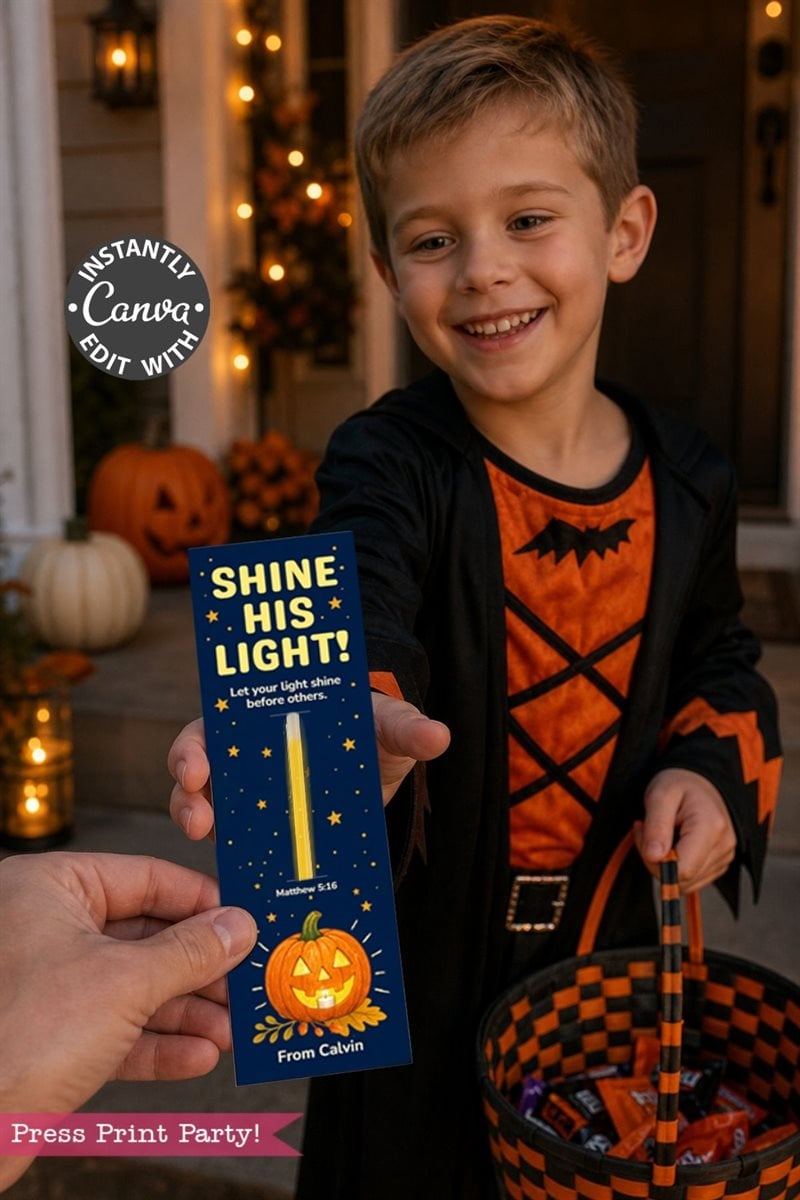 Smiling boy in a black and orange costume holds a Halloween candy basket and receives a card that says, “Shine His Light! Let your light shine before others,” with a pumpkin, stars, and Bible verse.