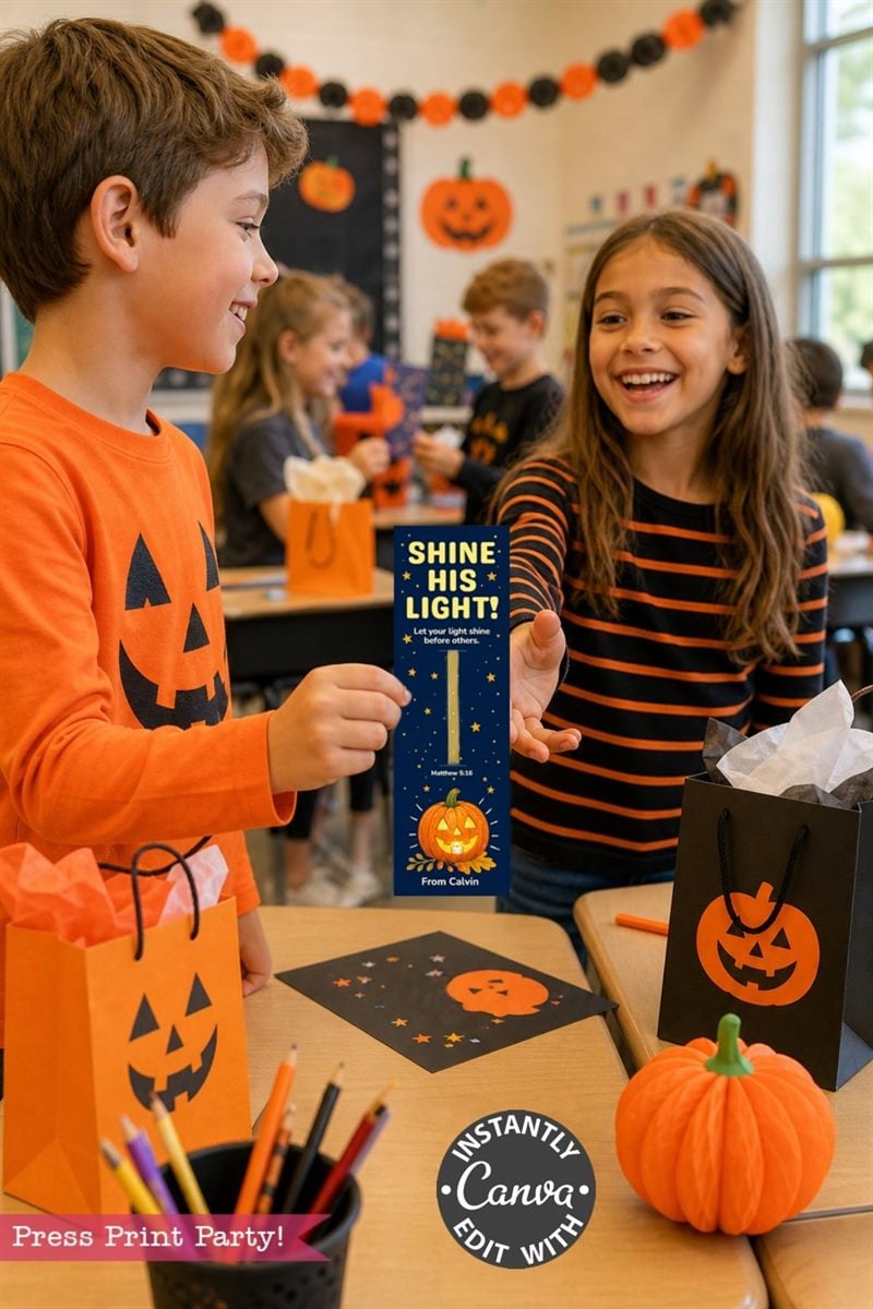Two smiling children in Halloween-themed clothes exchange a bookmark in a decorated classroom with pumpkins, gift bags, and festive decor visible on the tables and walls.
