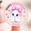 Add a sweet touch to your Halloween with these 6 Pink Coquette Halloween Ghost Round Labels, featuring a round sticker of a cute ghost wearing a pink bow, blushing and smiling, with the message “Happy Halloween! from Emma” in black and pink letters. Shown held on a fingertip—perfect for your festive labeling needs.