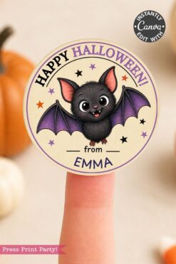 A finger puppet sticker with a cute cartoon bat, purple wings, and “Happy Halloween! from Emma” text. Small stars decorate the background. A pumpkin is blurred in the background.