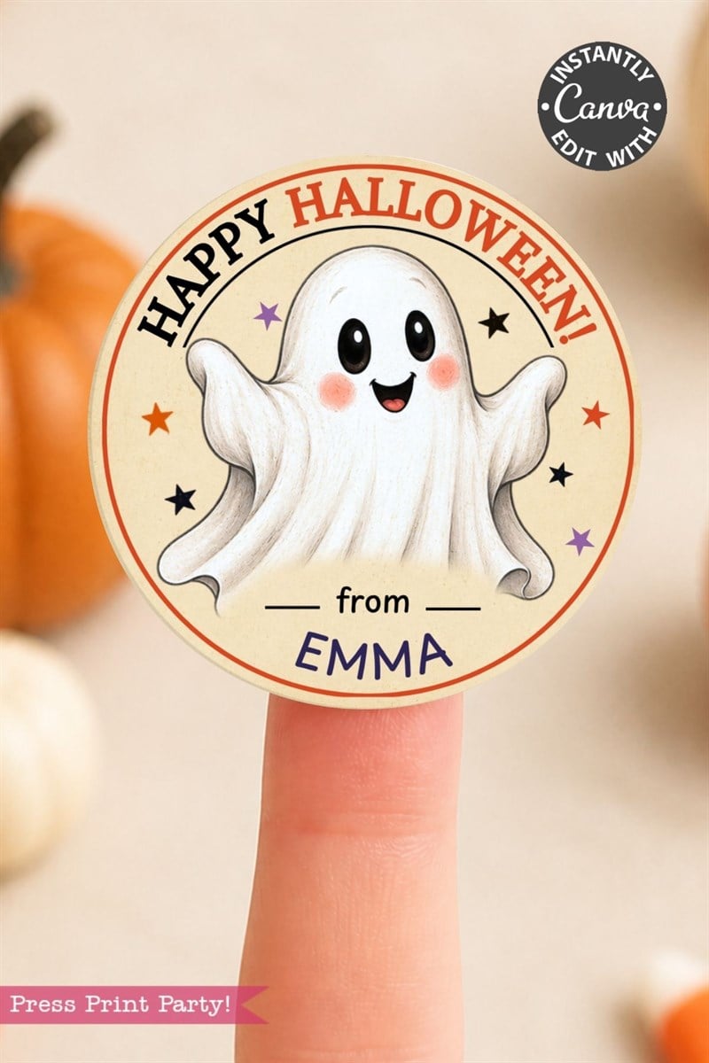 A round sticker on a fingertip shows a smiling ghost with “HAPPY HALLOWEEN! from EMMA” in colorful text, surrounded by stars. Pumpkins are blurred in the background.