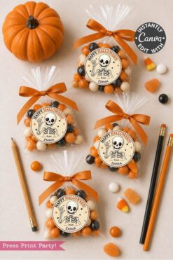Four clear treat bags with Halloween candy and skeleton labels, tied with orange ribbon, are arranged on a table with candy corn, pencils, a pencil sharpener, and a small pumpkin.