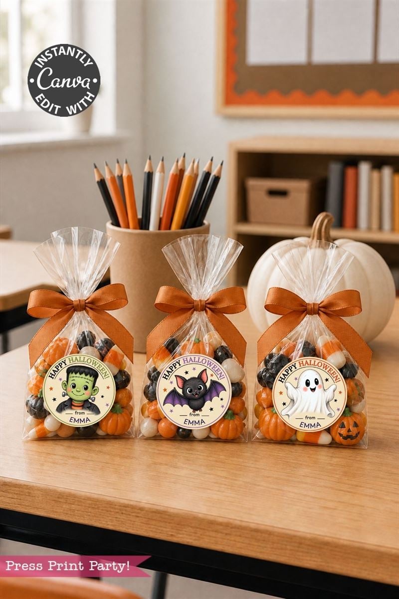 Three Halloween treat bags with orange bows each feature a cute character tag (Frankenstein, bat, ghost) and the name Emma. In the background are pencils, a white pumpkin, and autumn decor.