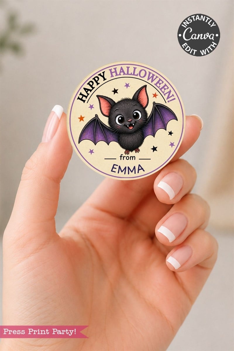 A hand holds a round, pink Coquette Ghost Treat Bag Halloween sticker featuring a cute bat with “Happy Halloween from Emma” written on it, along with stars and “Instantly Edit with Canva” in the corner.