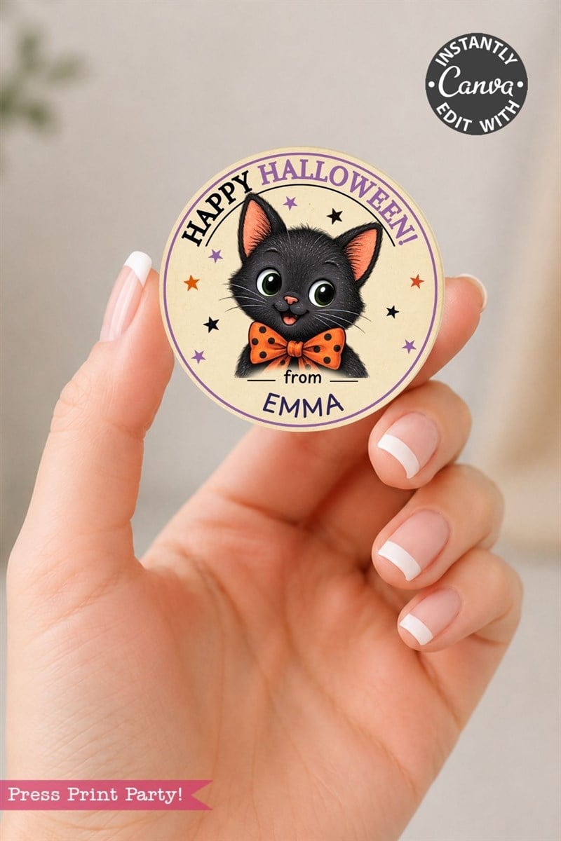A hand holds a round, pink Coquette Ghost Treat Bag Halloween sticker featuring a cute black cat with an orange bow tie and the message “Happy Halloween from Emma,” surrounded by stars.