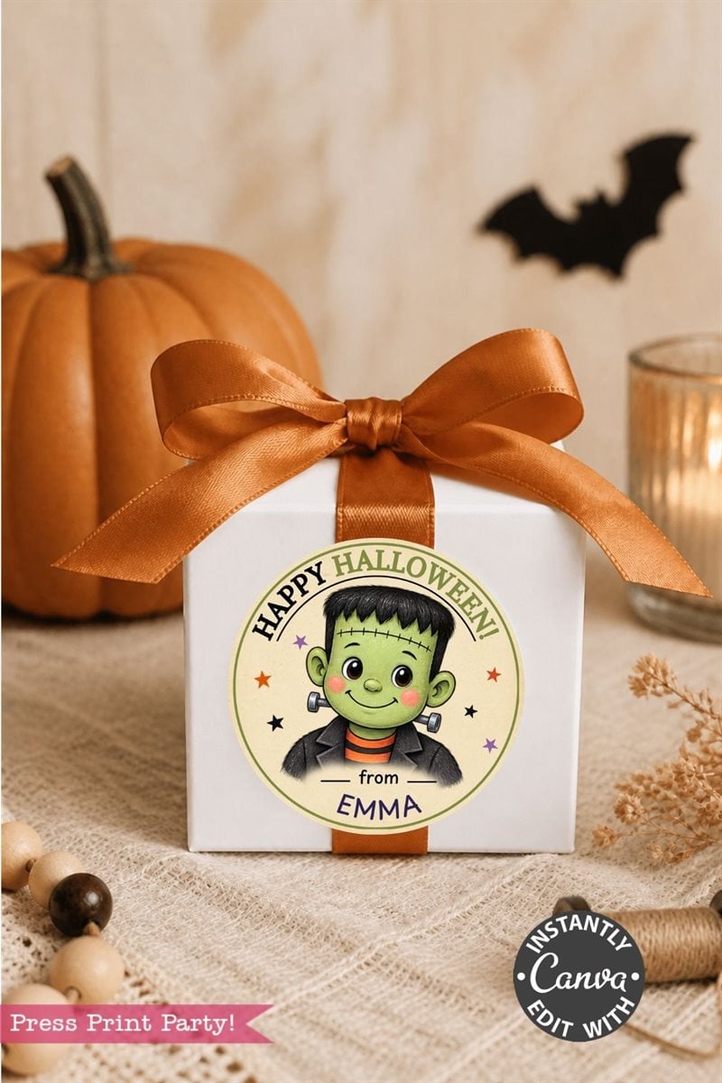 A white gift box with an orange ribbon, adorned with a Pink Coquette Ghost Treat Bag Halloween Sticker featuring a playful ghost design and “from EMMA.” The background includes a pumpkin, candle, bat decoration, and autumnal accents. Perfect for gifting, this box can be customized with these cute and stylish stickers to add a charming and coquette touch to your Halloween celebration.