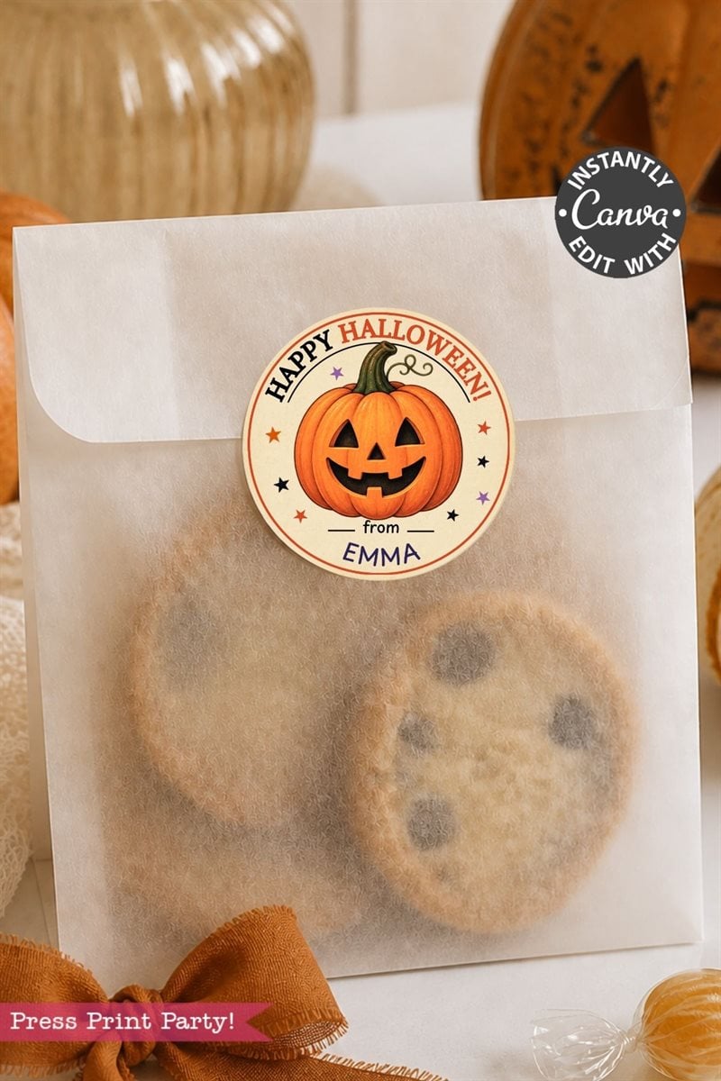 A translucent bag filled with chocolate chip cookies is sealed with a Pink Coquette Ghost Treat Bag Halloween Sticker, which showcases a smiling jack-o’-lantern and the text “Happy Halloween from Emma.” Orange decorations and pumpkins can be seen in the background.