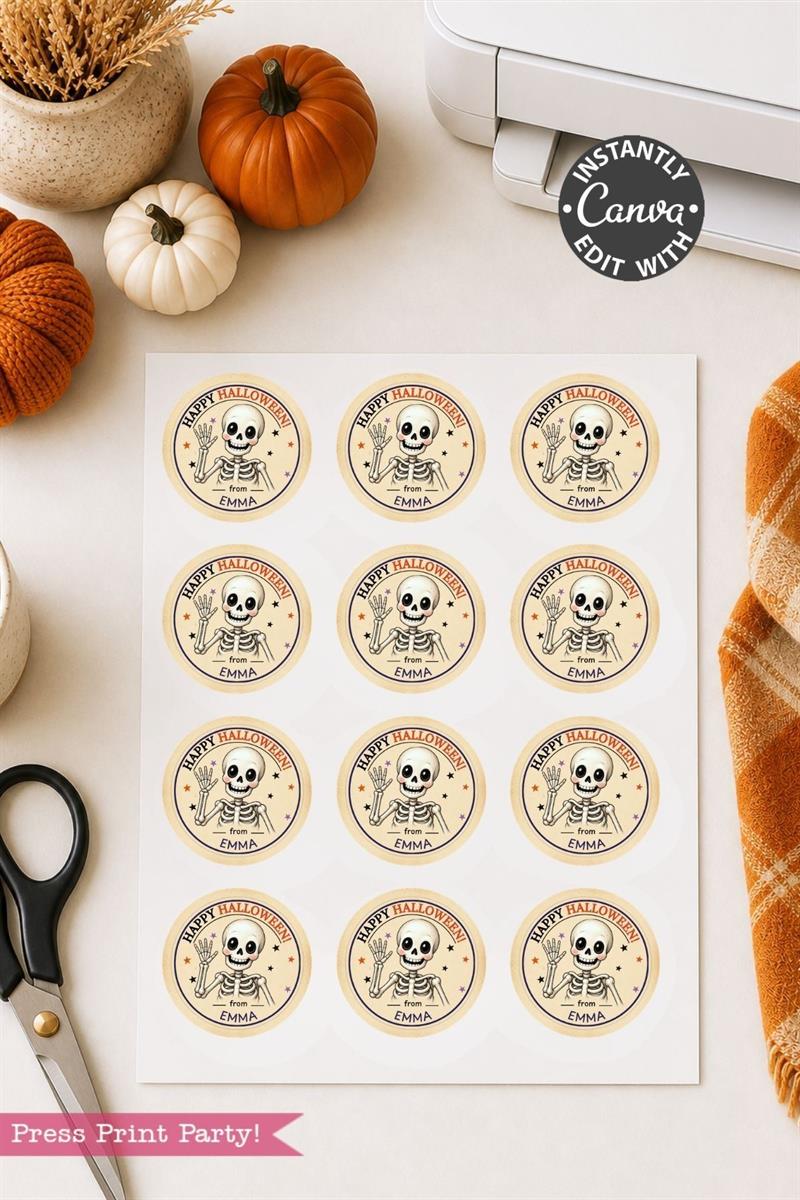 A sheet of Pink Coquette Ghost Treat Bag Halloween Stickers featuring a skeleton illustration and the text “Happy Halloween” sits on a desk surrounded by pumpkins, scissors, a printer, and an orange plaid cloth nearby.