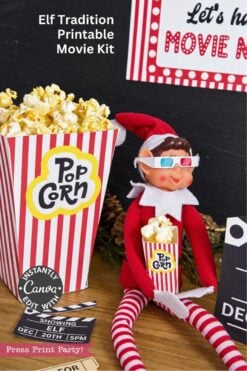 A toy elf wearing 3D glasses sits next to a striped popcorn container, accompanied by Elf Arrival Printable Bundle, Christmas Elf Kit movie-themed cards and a ticket stub.