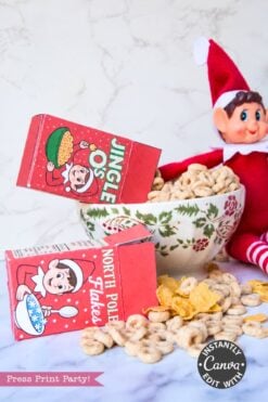 A toy elf sits behind a bowl of cereal for an Elf Arrival Printable Bundle, with miniature “Jingle O’s” and “North Pole Flakes” cereal boxes from the Christmas Elf Kit spilling into the bowl and onto the table.
