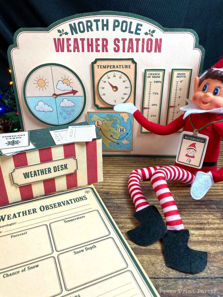 An elf toy sits next to a βNorth Pole Weather Stationβ sign with movable dials for temperature, snow depth, and chance of snow, accompanied by a weather desk and observation form.