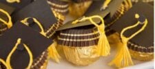 Gold-wrapped chocolates are decorated with brown paper graduation caps and yellow tassels, arranged closely together to resemble mini graduates.